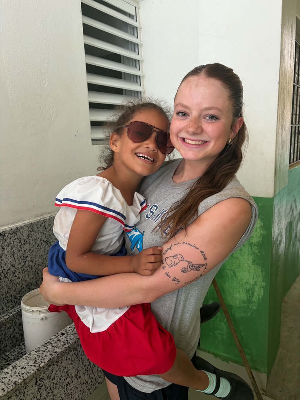 Sophia holding a young girl during an FNE service trip